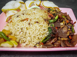 Traditional fried rice on a pink plate with a black and gray background