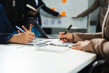 Business team calculate and analyzing graph document financial with laptop and digital tablet in office.