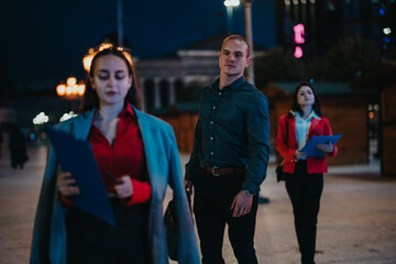 Obraz premium Three young creative professionals engaging in an outdoor business meeting at night, discussing project ideas and plans