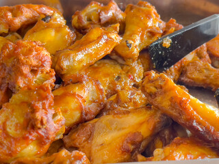 A plate of fried chicken wings with a black spatula