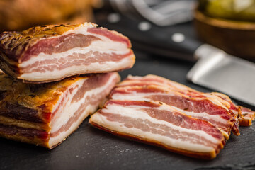 Closeup of Sliced Smoked Bacon on Black Slate Cutting Board