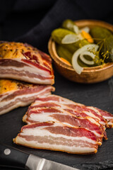 Closeup of Sliced Smoked Bacon on Black Slate Cutting Board