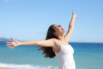 Joyful woman in white dress outstretching arms on the beach