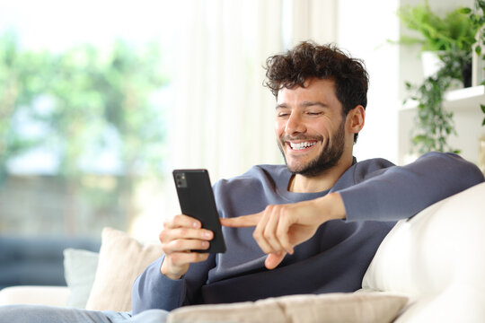 Happy man using smart phone in a house interior - Powered by Adobe