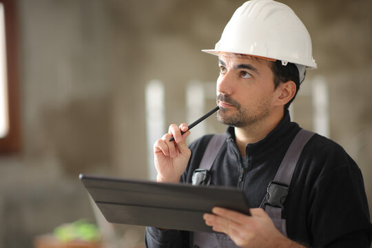 Pensive construction worker holding tablet