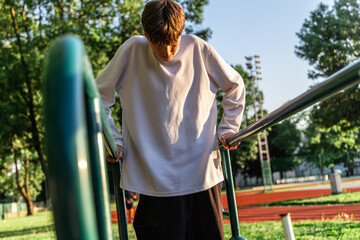Young Man Exercising on Parallel Bars at Outdoor Gym