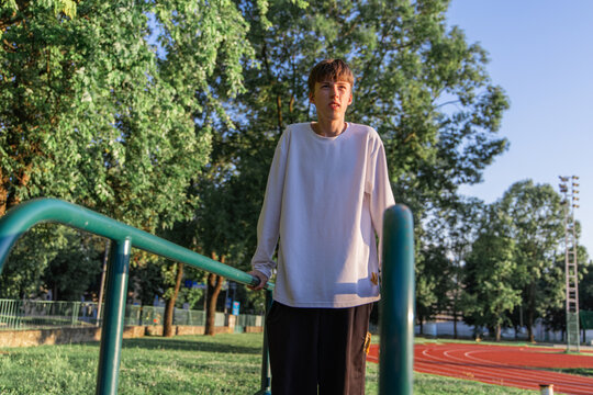 Young Man Exercising On Parallel Bars At Park