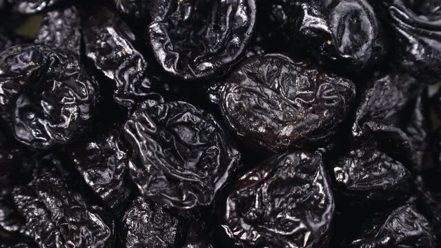 Black prunes or dried plums circle rotation close up top view