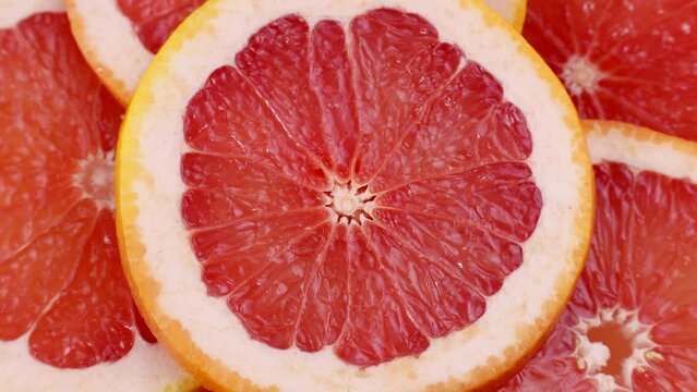 Bright pink and red grapefruit slices circle rotation close up