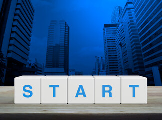 Start letter on white block cubes on wooden table over modern office city tower and skyscraper,...