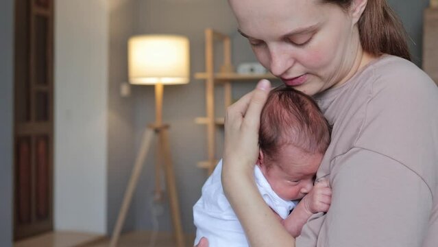 Calm newborn is sleeping peacefully in his mother hands woman gently kissing infant head female enjoying first days of her motherhood