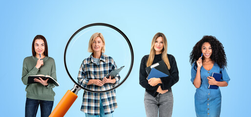 Four women holding notebooks and folders, standing on a light bl
