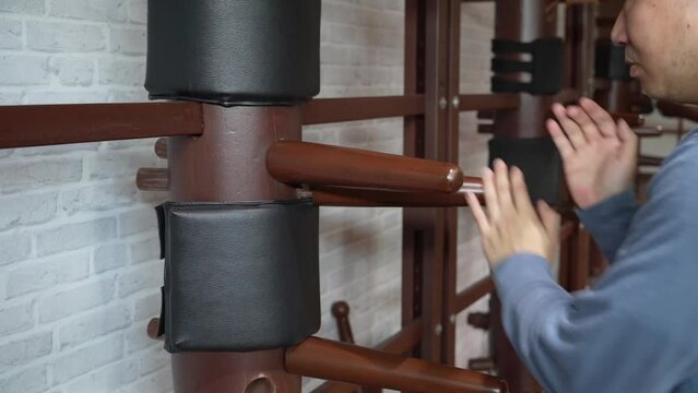 Slow motion, man training in Wing Chun Kung Fu with wooden dummy. The athlete shows techniques Wing Chun KungFu wooden dummy