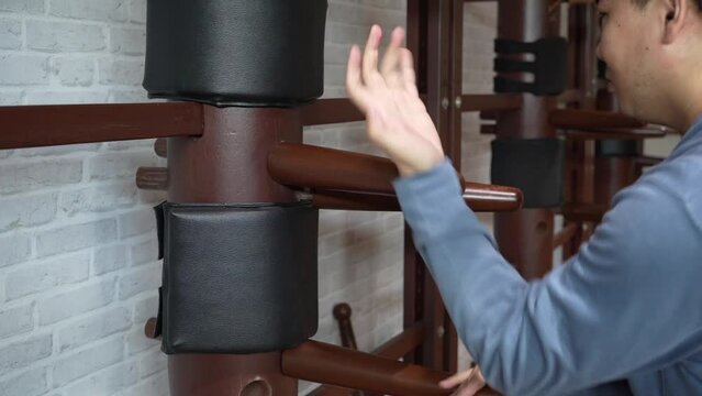 Slow motion, man training in Wing Chun Kung Fu with wooden dummy. The athlete shows techniques Wing Chun KungFu wooden dummy