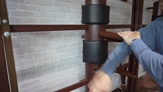 man training in Wing Chun Kung Fu with wooden dummy. The athlete shows techniques Wing Chun KungFu wooden dummy.	