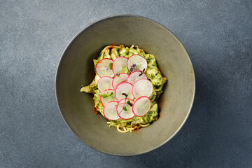 Spaghetti with pesto sauce and radish. In a plate. Close up.