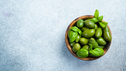 A wooden bowl with marinated olives. on a gray concrete background. Close up.