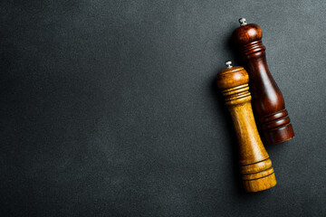 Vintage wooden pepper mill on black stone table. Preparation for cooking. Mockup, free space for...