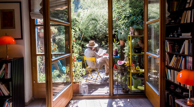 Man wearing hat and reading book on chair in garden