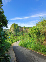 cliff on the side of the road with a blue sky as a background during the day in Bukittinggi, West Sumatra