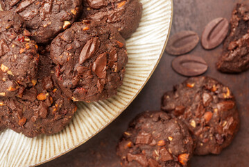 double chocolate cookies in ceramic plate on rusty background.
