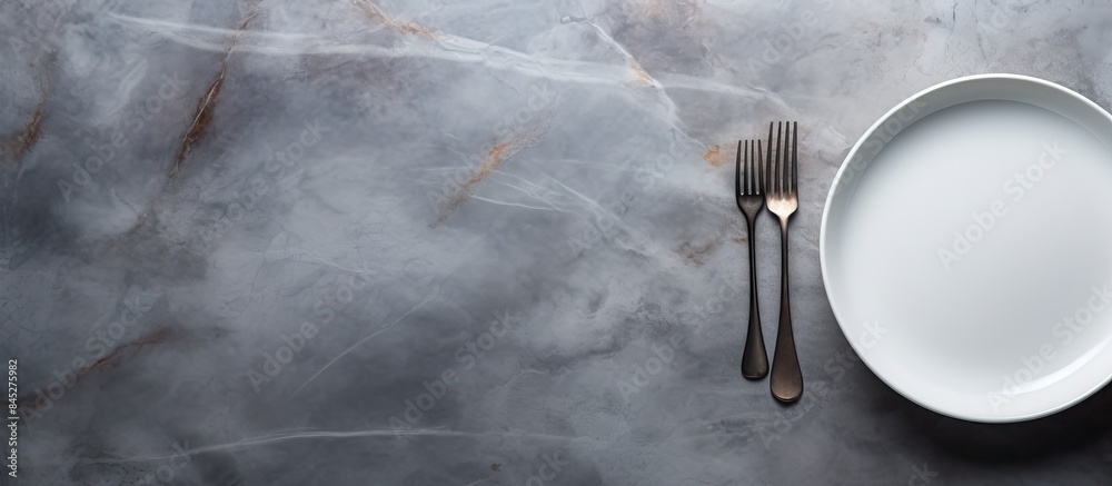 Aufkleber A top down view of a gray stone table with an empty white ceramic plate accompanied by a fork and knife There is ample copy space in the image