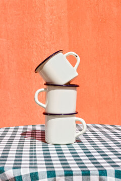 Stack of tea cups on table in front of orange wall