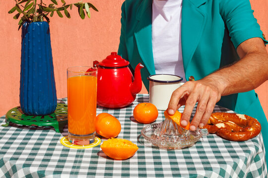Mature man squeezing oranges and having breakfast at terrace