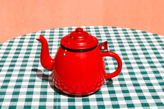 Red colored tea kettle on table at terrace