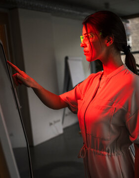 Young businesswoman wearing smart glasses and touching computer screen in office