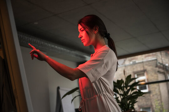 Young businesswoman touching computer with red light in modern office