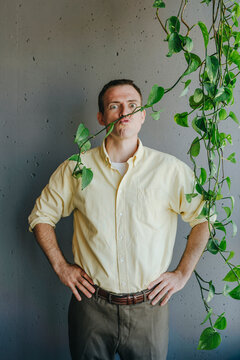 Shocked businessman with twig over lips standing in front of wall