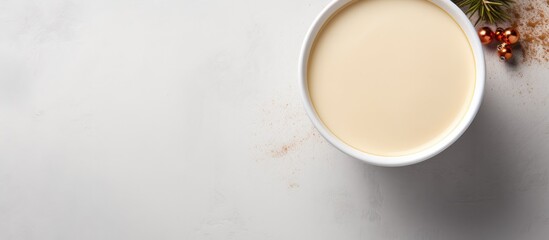 A festive holiday beverage concept featuring Christmas eggnog in a white cup against a gray tile background viewed from the top with copy space available for the image