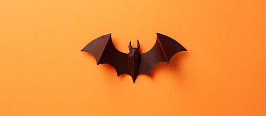 Fototapeta premium A Halloween themed craft featuring a paper bat cut out from a template and placed on an orange background with a white square The image provides copy space for text and is captured from a top down pe