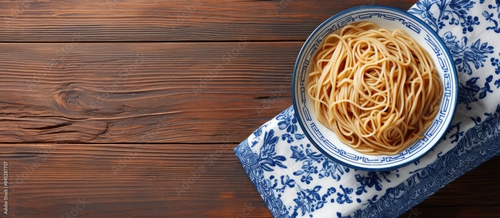 Poster a top down view of a plate of noodles on a wooden table accompanied by wooden chopsticks set against