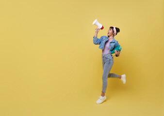 Young Asian teen college student holding megaphone announce isolated on yellow copy space background. Speech and announce back to school concept.