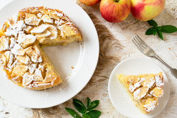 Easy Italian apple cake on a white dish, with red apples in the background.