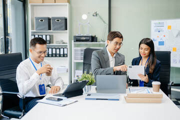Happy Asian businesspeople while collaborating on a new project.  using a laptop and tablet