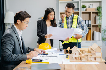 Engineer teams meeting working together wear worker helmets hardhat with on architectural project site and making model house. Asian industry professional team