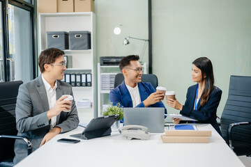 Happy Asian businesspeople while collaborating on a new project.  using a laptop and tablet