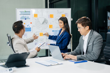 Office colleagues have a casual discussion. During a meeting in a conference room, a group of Asian business teem sit in the conference room