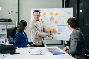 Office colleagues have a casual discussion. During a meeting in a conference room, a group of Asian business teem sit in the conference room