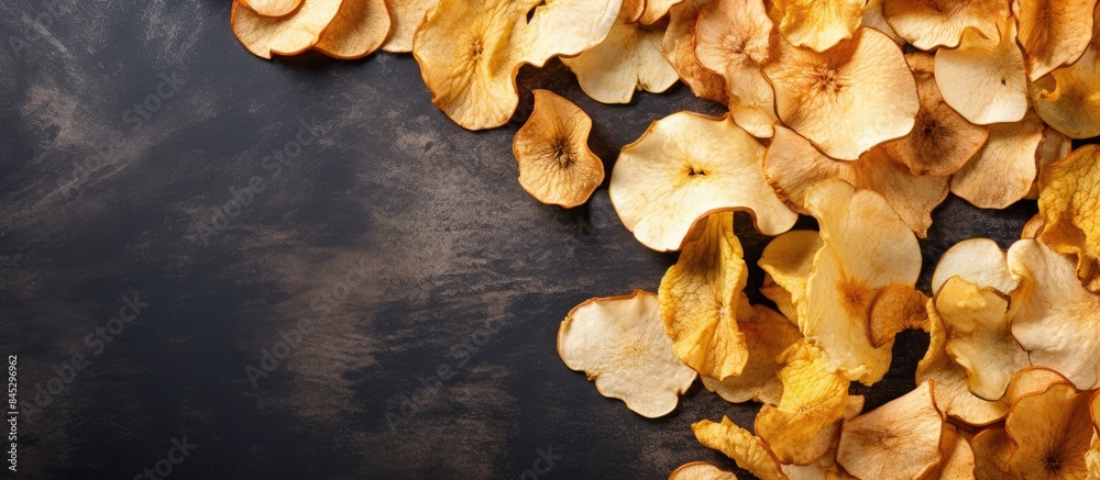 Poster A top view of organic dried apple chips arranged on a gray textile background creating an image that showcases the natural and healthy aspect of the food Flat lay presentation with ample copy space