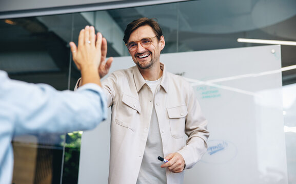 Business man high fiving his colleague in celebration of their success as a team - Powered by Adobe