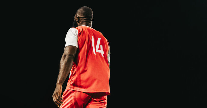 Professional football player in red jersey number 14 on the field at night