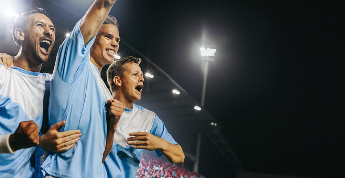 Professional football players celebrating a winning goal at a championship match in a full stadium