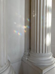 Aristocratic aesthetics of classic white columns with flutes. Refractions of light are visible on the columns, creating multicolored highlights.