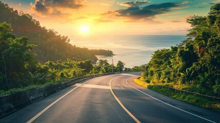 Naklejka premium Empty highway, dense tropical forest on one side of the road and sea coast on the other, , sky illuminated by the sun's rays at sunset, incredible nature