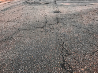 A cracked and broken road with a hole in the middle