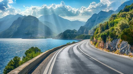 Obraz premium Empty highway on the background of steep mountain peaks, sea coast on one side of the road, blue water, clear sunny day, bright rays